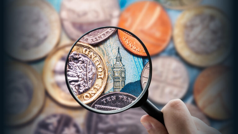 Magnifying glass looking at a pile of coins and paper money. The magnified section is clear, and the rest of the image is blurred. Fast business lending.