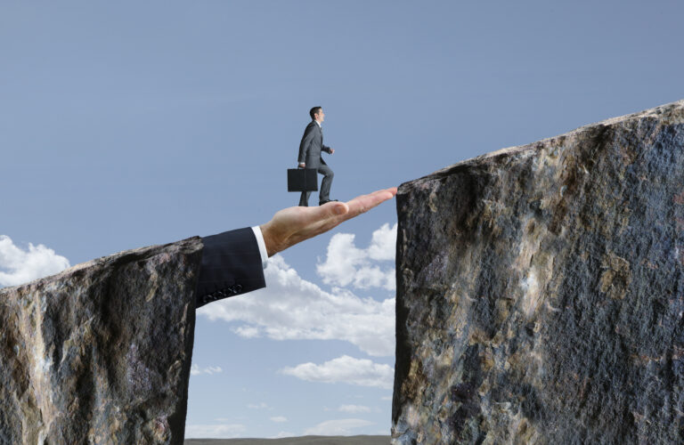 A giant hand in a business suit creating a bridge between two cliffs for a small businessman. Symbolic representation of bridging finance for small to medium enterprises (SMEs).